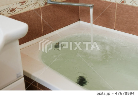 Strong stream of water pours into the tub. Water pours out. Tub overflows. Close up. 47678994