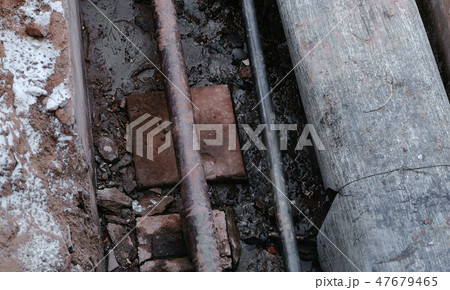 Closeup crash, burst pipes and leaking water under the earth. Excavated pipes in the winter. 47679465