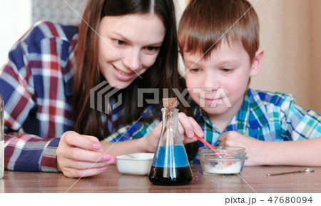 Chemistry experiments at home. Mom and son make a chemical reaction with the release of gas in the Chemistry experiments at home. Mom and son make a chemical reaction with the release of gas in the 47680094