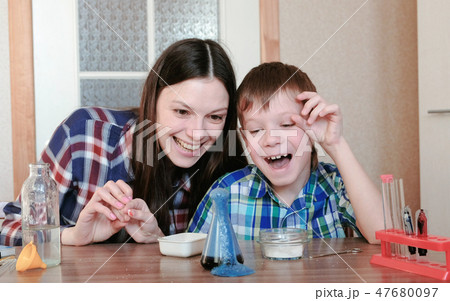 Chemistry experiments at home. Happy Mom and son make a chemical reaction with the release of gas in 47680097