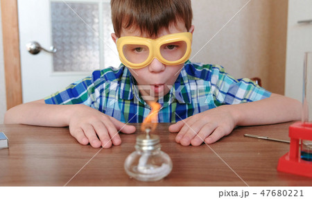 Experiments on chemistry at home. Surprised Boy is looking at the burning alcohol lamp on fire with Experiments on chemistry at home. Surprised Boy is looking at the burning alcohol lamp on fire with 47680221