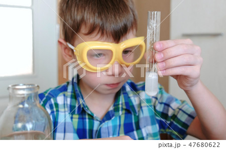 Experiments on chemistry at home. Boy is looking Chemical reaction with the release of gas in a test Experiments on chemistry at home. Boy is looking Chemical reaction with the release of gas in a test 47680622