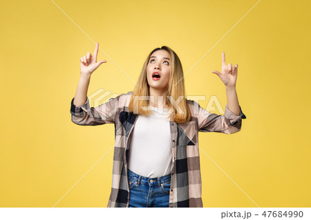 Smiling woman pointing finger side. Isolated portrait on yellow. 47684990