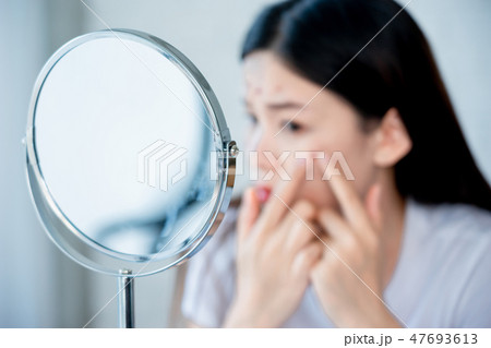 Asian teenage girl looking at acne problem on face Asian teenage girl looking at acne problem on face 47693613