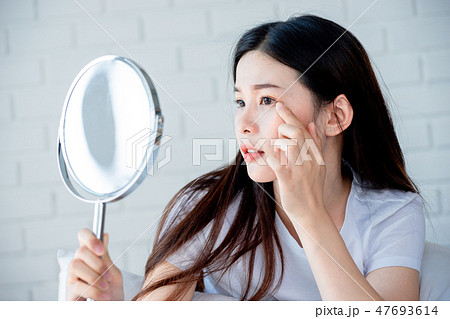 Asian teenage girl looking at acne problem on face 47693614
