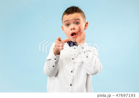 The teen boy whispering a secret behind her hand over blue background The teen boy whispering a secret behind her hand over blue background 47697193