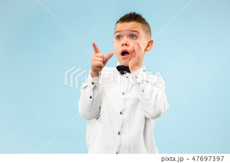 The young attractive teen boy looking suprised isolated on blue The young attractive teen boy looking suprised isolated on blue 47697397