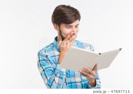 Education, leisure and people concept - young beard man reading a book and surprised Education, leisure and people concept - young beard man reading a book and surprised 47697713