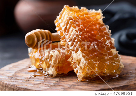 Honeycomb and honey dipper on wooden board Honeycomb and honey dipper on wooden board 47699951