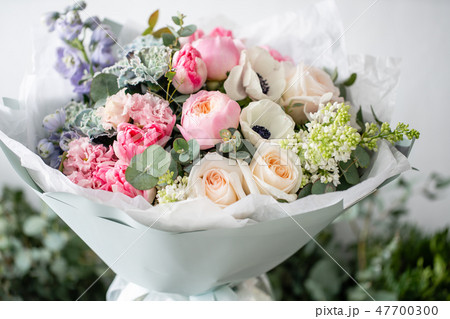beautiful fresh cut bouquet of mixed flowers in vase on wooden table. The work of the florist at a 47700300