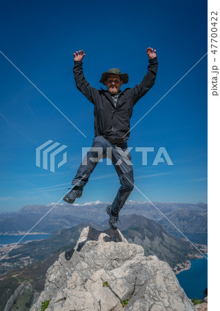 Tourist with a hat jumping high in the air Tourist with a hat jumping high in the air 47700422