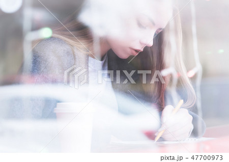 Portrait of an attractive young journalist girl with pen and notepad in cafe behind the showcase Portrait of an attractive young journalist girl with pen and notepad in cafe behind the showcase 47700973