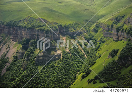 Dramatic landscape of a green valley at the foot of the Inal Plateau in the North Caucasus 47700975