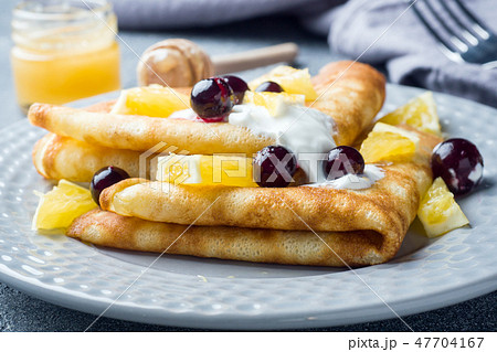 A portion of pancakes with berries and cream  47704167