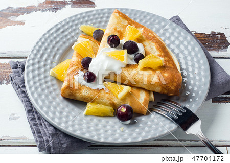 A portion of pancakes with berries and cream  47704172