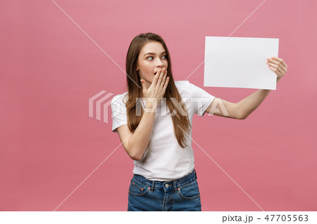 Young caucasian woman holding blank paper sheet over isolated background scared in shock with a Young caucasian woman holding blank paper sheet over isolated background scared in shock with a 47705563