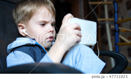 The boy listens to music through headphones. In the children's room the child enjoys music The boy listens to music through headphones. In the children's room the child enjoys music 47711023