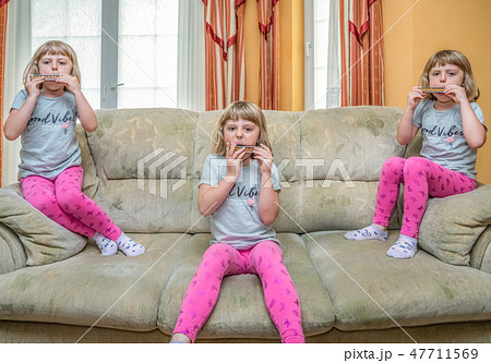 Girls playing harmonica at home Girls playing harmonica at home 47711569