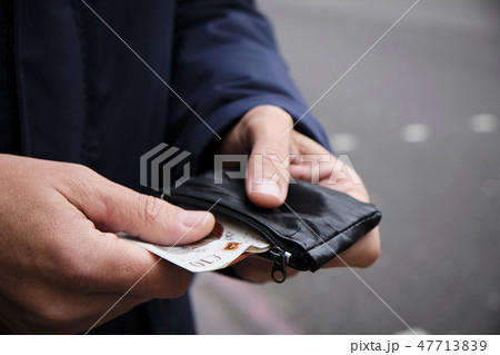 man putting in or taking off money from his wallet 47713839