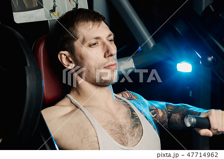 Handsome athletic man trains pectoral muscles on a 47714962