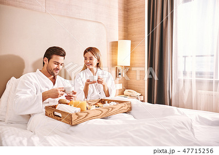 Food delivery in the room. Couple are eating in hotel room bed Food delivery in the room. Couple are eating in hotel room bed 47715256
