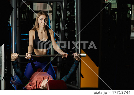 Female trainer helping guy to train in the gym Bar Female trainer helping guy to train in the gym Bar 47715744