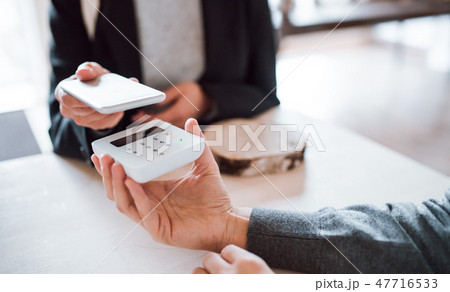 A midsection of customer and shop assistant making mobile payment in a shop. 47716533