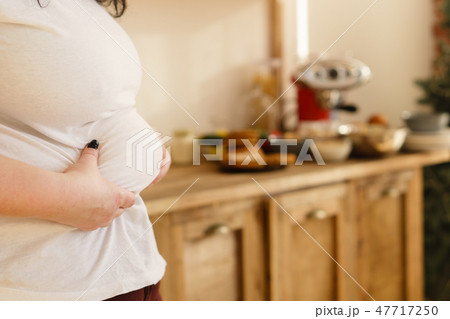 overweight woman hands touching belly fat 47717250