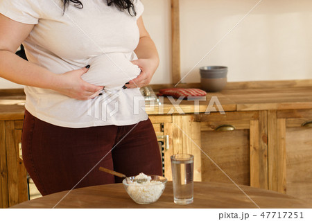 overweight woman hands touching belly fat 47717251