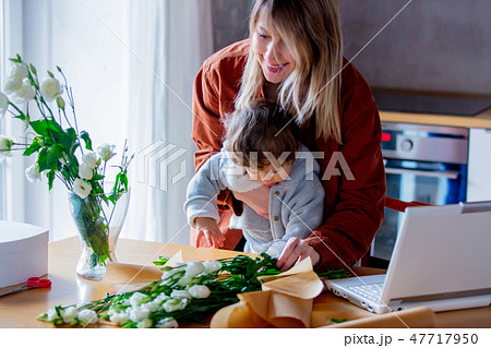 Mother with a child trying to working as a florist businesswoman 47717950
