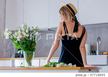 girl dressed in a black dress near white roses bouquet in a vase 47718005