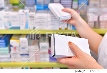 Pharmacist holding medicine box in pharmacy  47719882