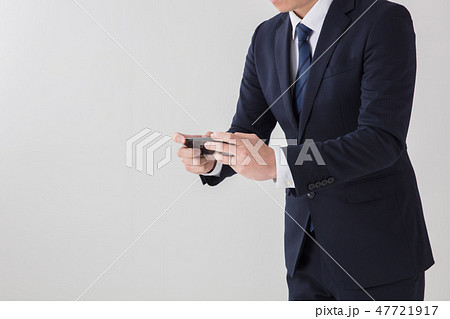 白背景で上半身でスーツの男性がスマートフォンを休憩中にゲームをしている場面 白背景で上半身でスーツの男性がスマートフォンを休憩中にゲームをしている場面 47721917