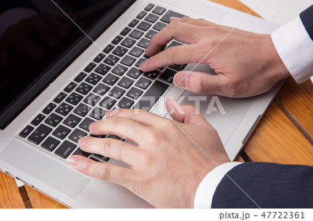 机でスーツの男性が手元アップでパソコンでタイピングをして仕事をしているの写真素材