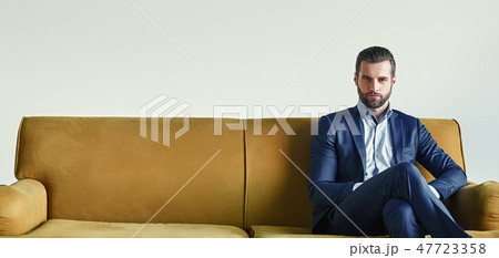 Waiting for a meeting...Well-dressed young and successful businessman is sitting on sofa at office 47723358
