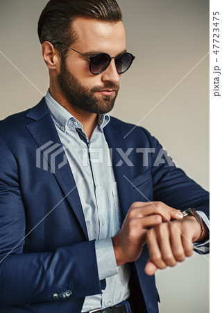 Time is money...Busy handsome businessman in stylish suit and sunglasses is checking time while 47723475