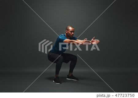 Work hard to become the best. Sportsman is stretching standing over dark background Work hard to become the best. Sportsman is stretching standing over dark background 47723750