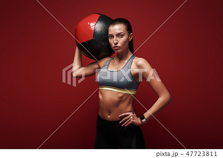 Create healthy habits, not restrictions. Sportswoman holds exercise ball standing over red 47723811