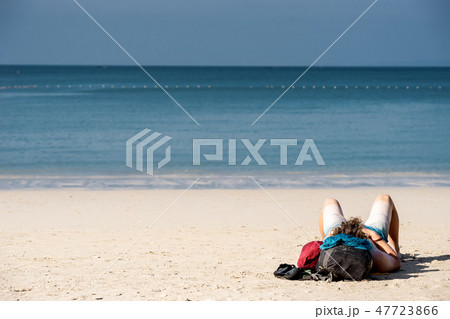A tourist guy sleeping on white-yellow sand beach 47723866
