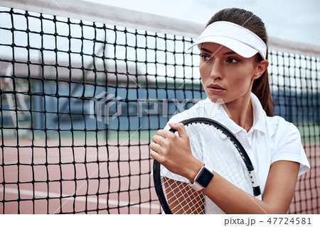 You can do it! Portrait of young beautiful woman with a racket on a court, looking away. You can do it! Portrait of young beautiful woman with a racket on a court, looking away. 47724581
