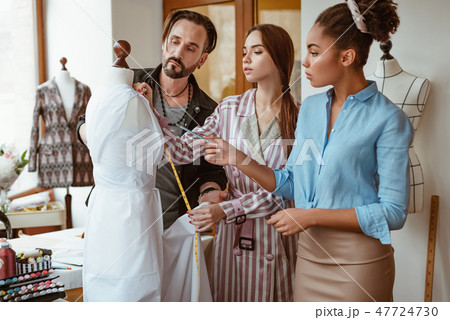 Discuss measurements for new dress.Young fashion designer taking measurements Discuss measurements for new dress.Young fashion designer taking measurements 47724730