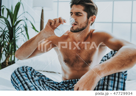 Guy drinking water with pill after hang-over Guy drinking water with pill after hang-over 47729934