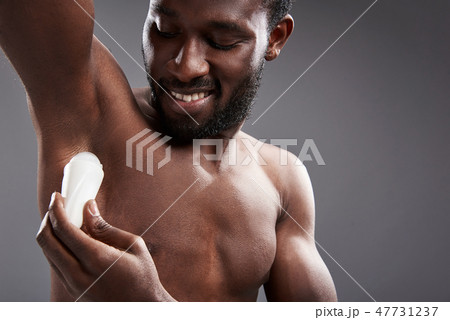 Joyful handsome afro American man using his deodorant Joyful handsome afro American man using his deodorant 47731237