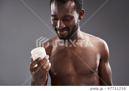 Cheerful handsome afro America man holding a cream jar Cheerful handsome afro America man holding a cream jar 47731258