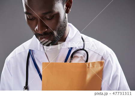 Serious afro american male doctor standing against gray background 47731311