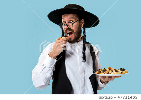 The young orthodox Jewish man with black hat with Hamantaschen cookies for Jewish festival of Purim 47731405