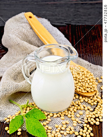 Milk soy in jug with spoon and leaf on dark board 47732816