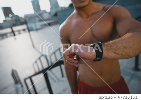 Bare-chested male watching at digital device outside 47733133
