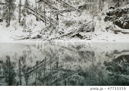 Lake with ice reflecting snow covered mountains.  47733359
