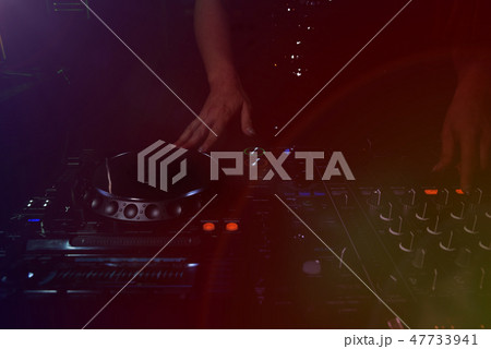 Hands of female DJ adjusting sound during disco pa 47733941